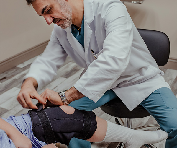 Doctor tryin a brace on a patient's knee